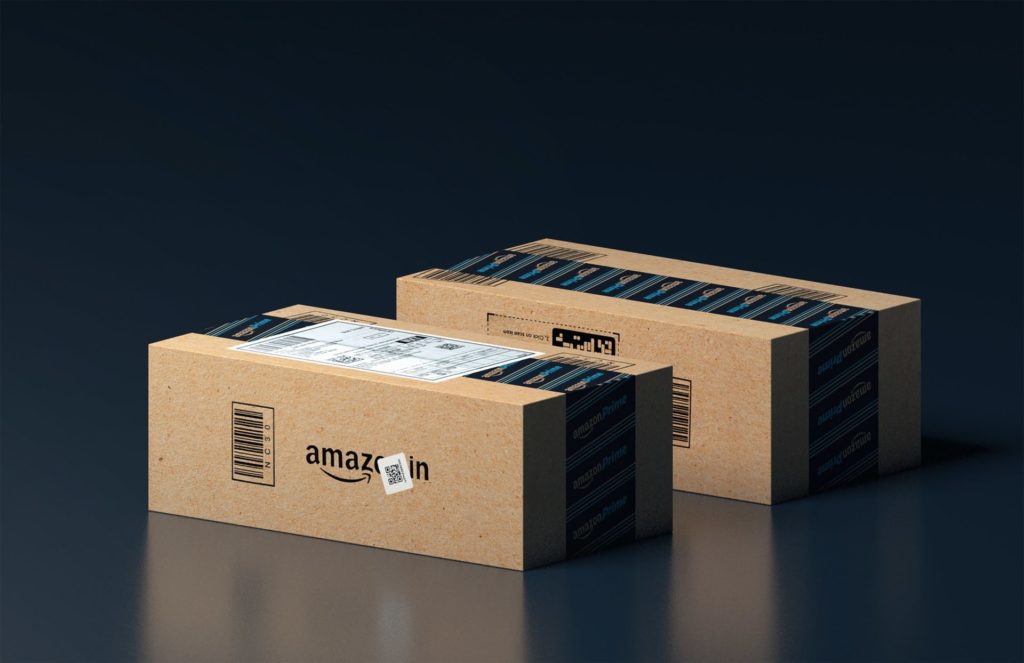 Two brown, unopened Amazon boxes against a black reflective background.